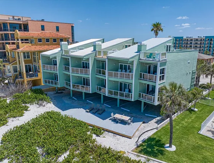 Modern beachfront condominiums with distinctive green siding and white roofs situated along a pristine coastal setting.