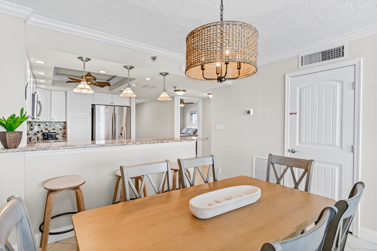 Gather around your spacious dining table beneath the warm glow of woven lighting, with the modern kitchen just steps away for easy entertaining.