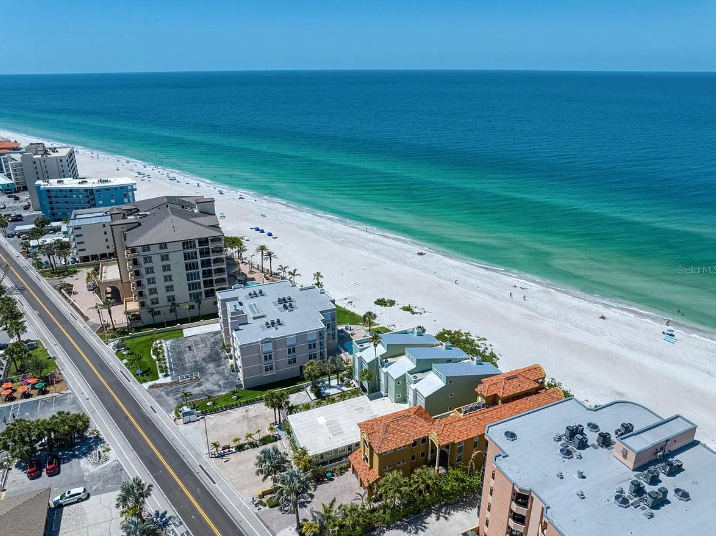 Stunning aerial view of beachfront properties along pristine white sand and emerald Gulf waters.