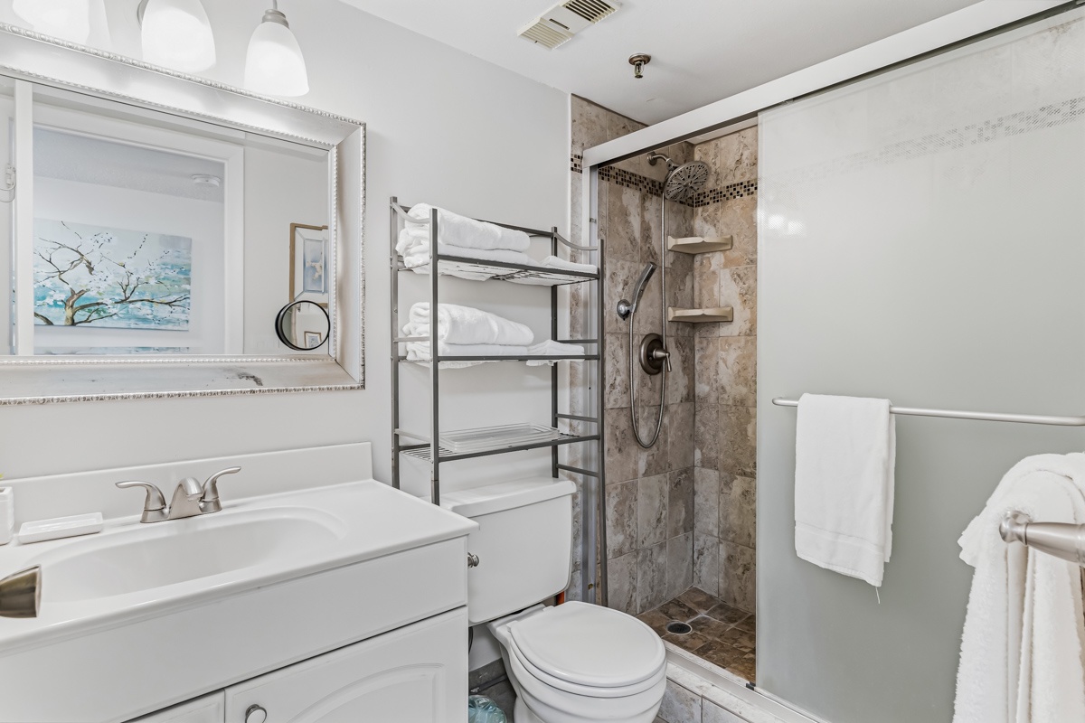 Your bathroom offers everything you need to unwind after a day of adventure—crisp towels, a sleek vanity, and a spacious step-in shower with elegant stonework.