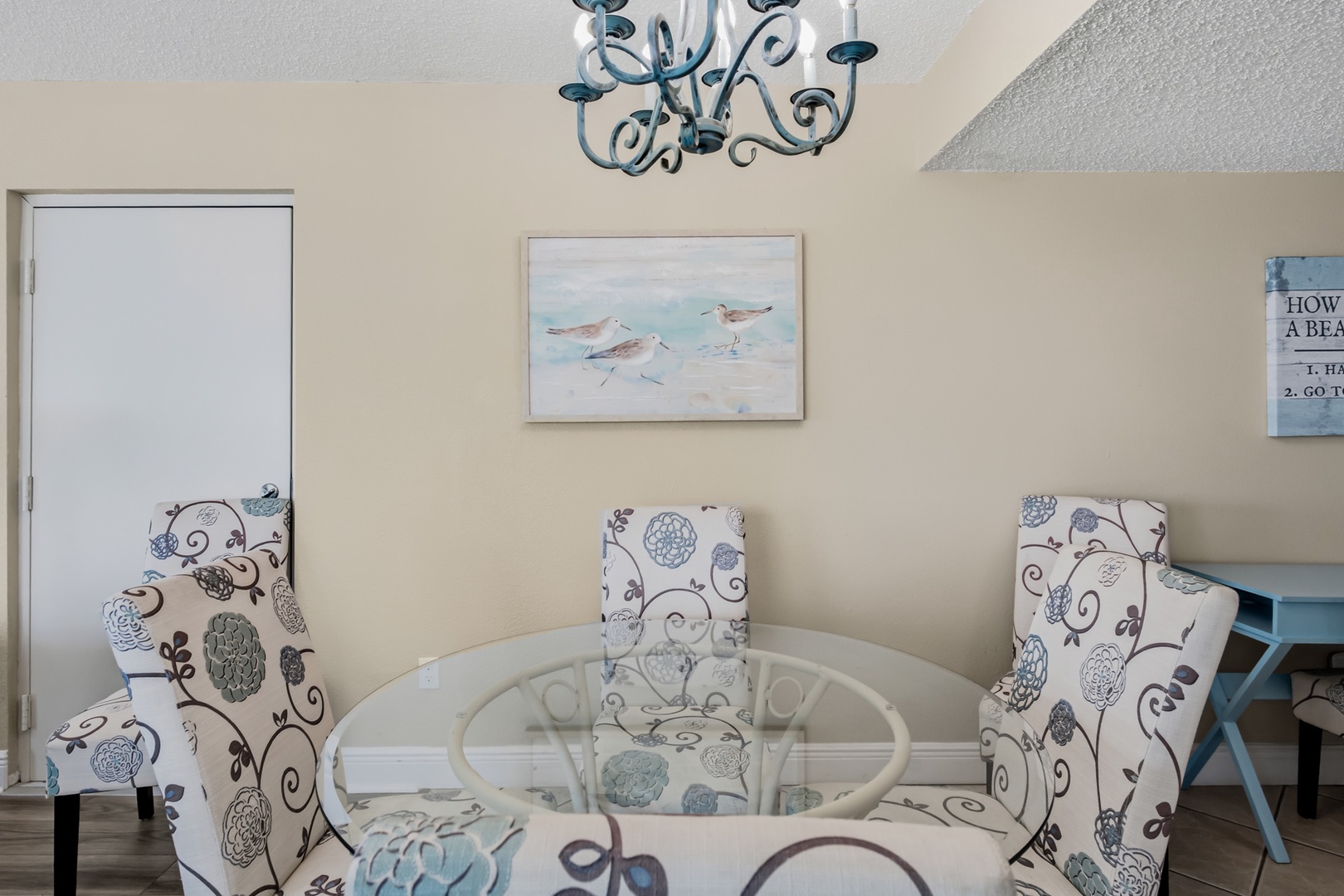 Settle into coastal charm at your glass-top dining table, where whimsical chairs and soft seaside hues create the perfect spot for morning coffee or evening meals together.