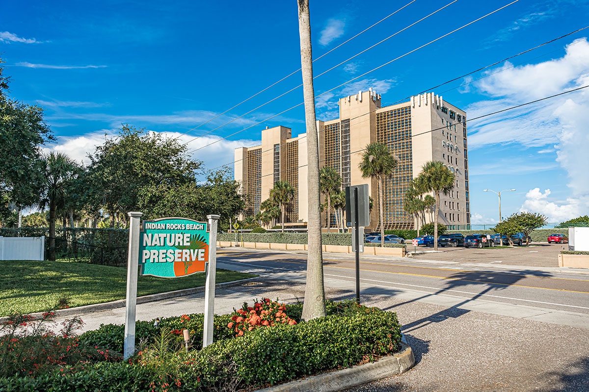 Indian Rocks Beach Nature Preserve sign welcomes visitors to this protected coastal area near towering beachfront buildings.