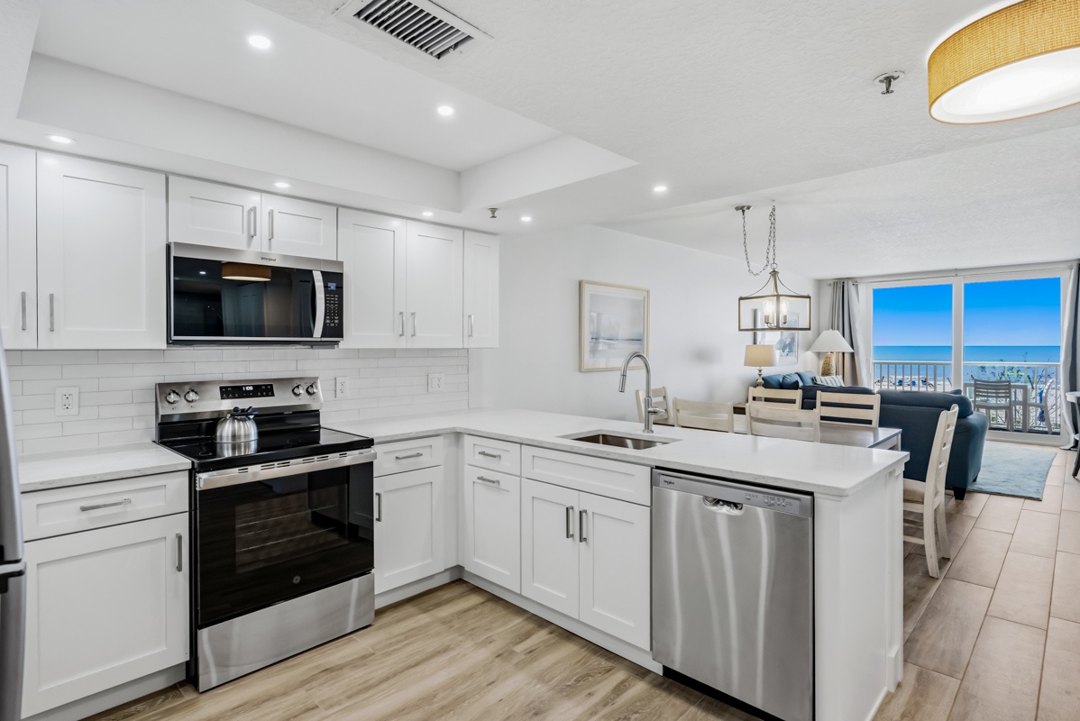 Your modern kitchen features sleek white cabinets, stainless steel appliances, and stunning ocean views from every window.
