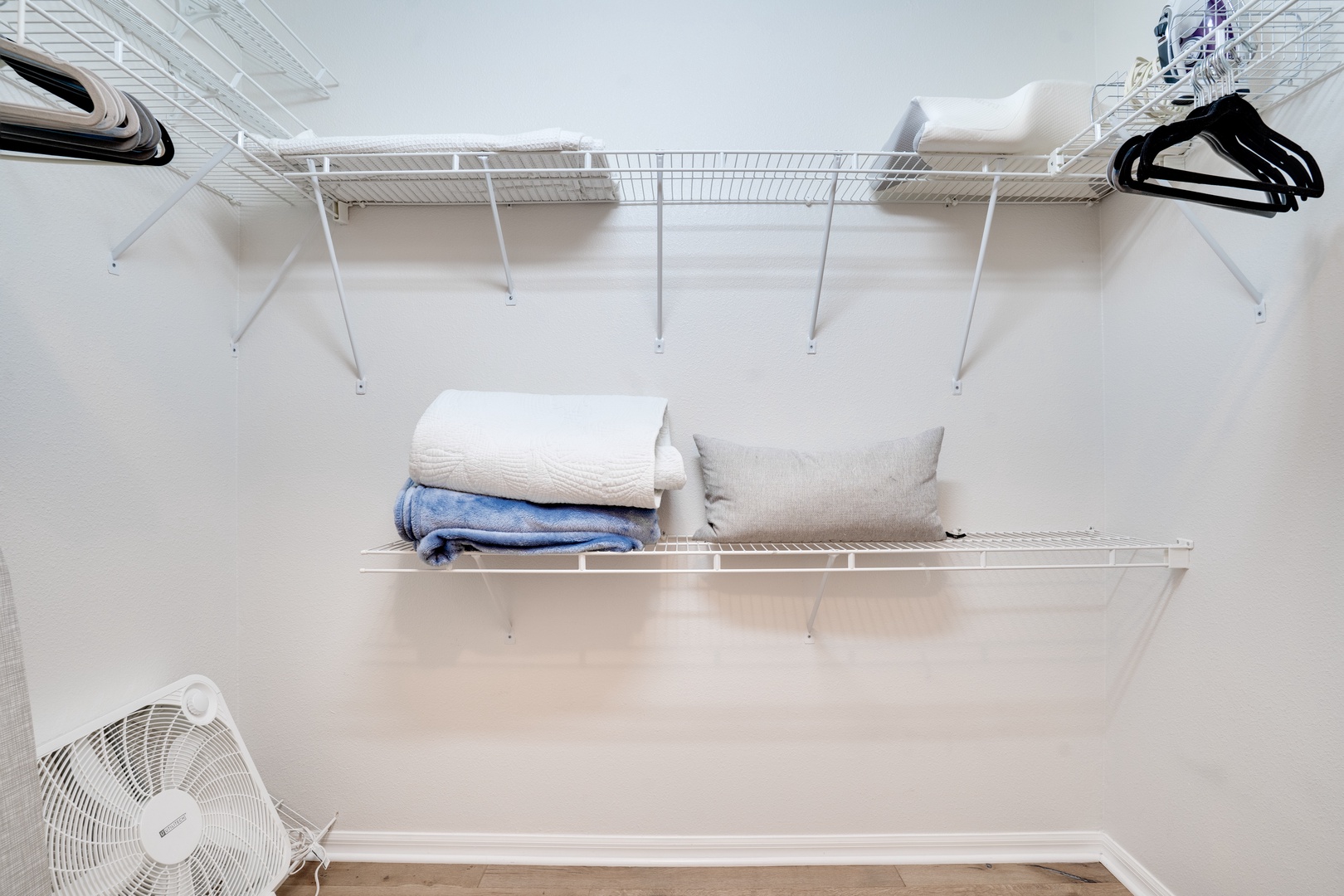 Your walk-in closet offers generous space with wire shelving, hangers, and a fan for comfort while you organize.