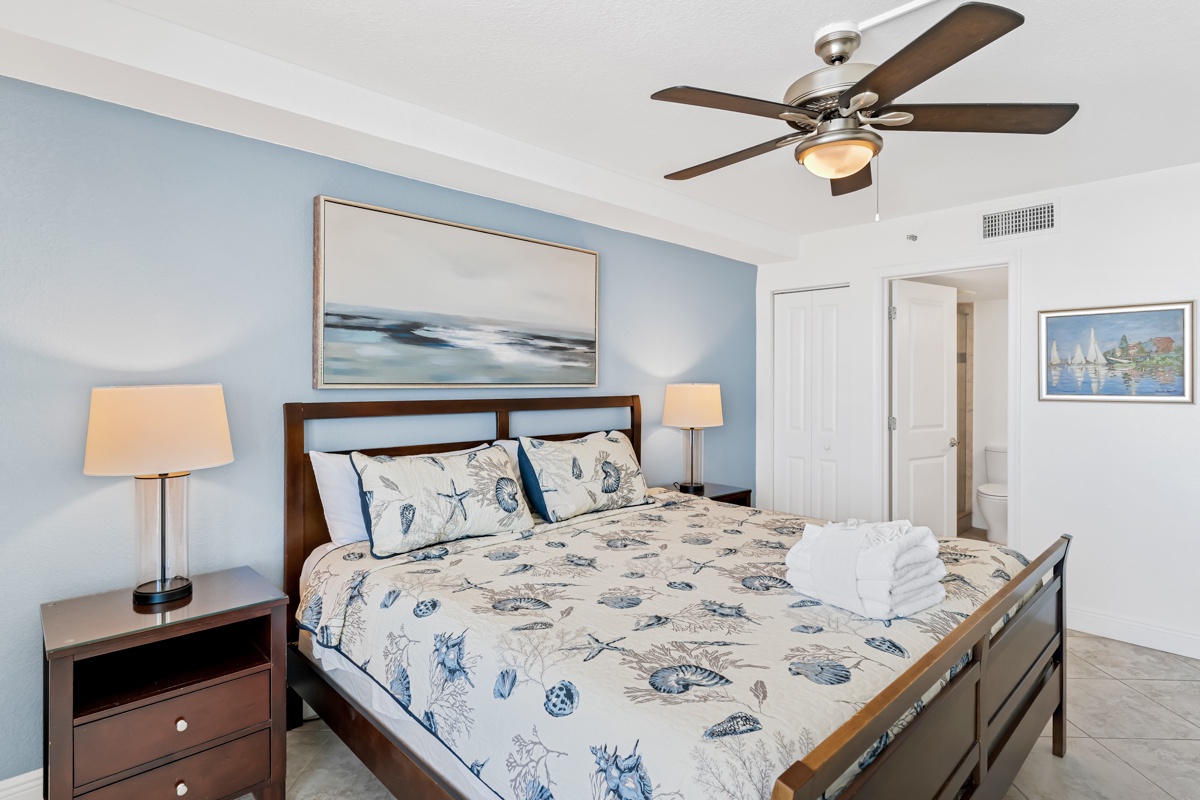 Your bedroom features coastal-themed bedding, warm lighting, and ceiling fan comfort for peaceful nights.