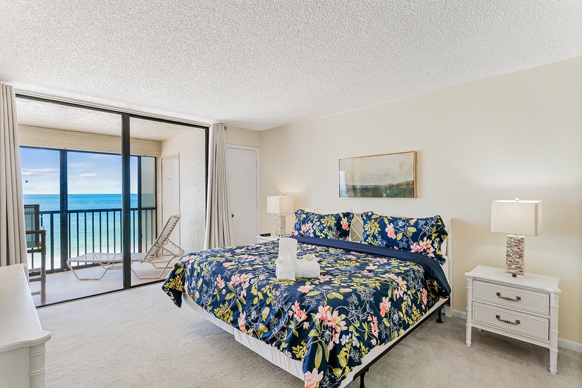 Wake to ocean waves from your coastal bedroom, featuring vibrant floral bedding and direct balcony access to endless sea views.