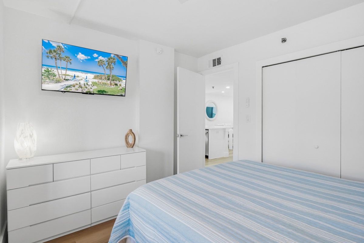 Unwind in your serene white bedroom with tropical TV views, ample storage, and convenient ensuite access.