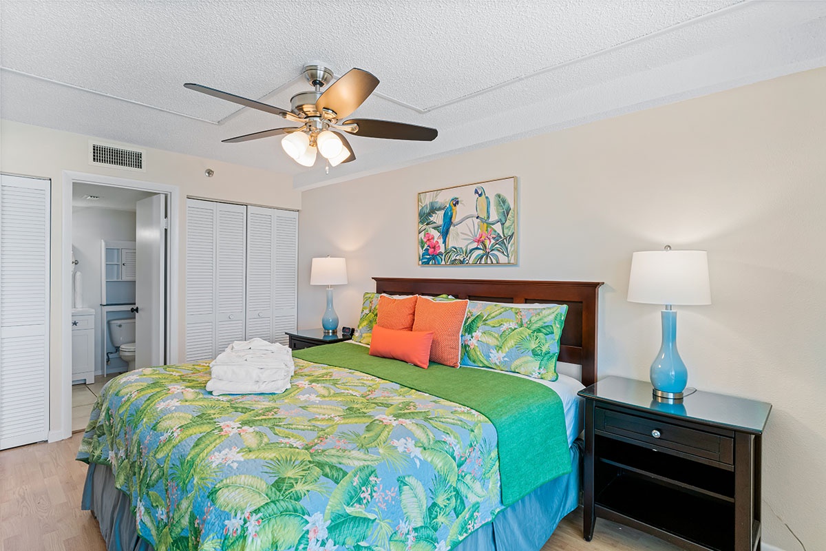 Drift off in your tropical-themed bedroom with vibrant bedding, gentle ceiling fan, and cheerful artwork creating a perfect island retreat atmosphere.