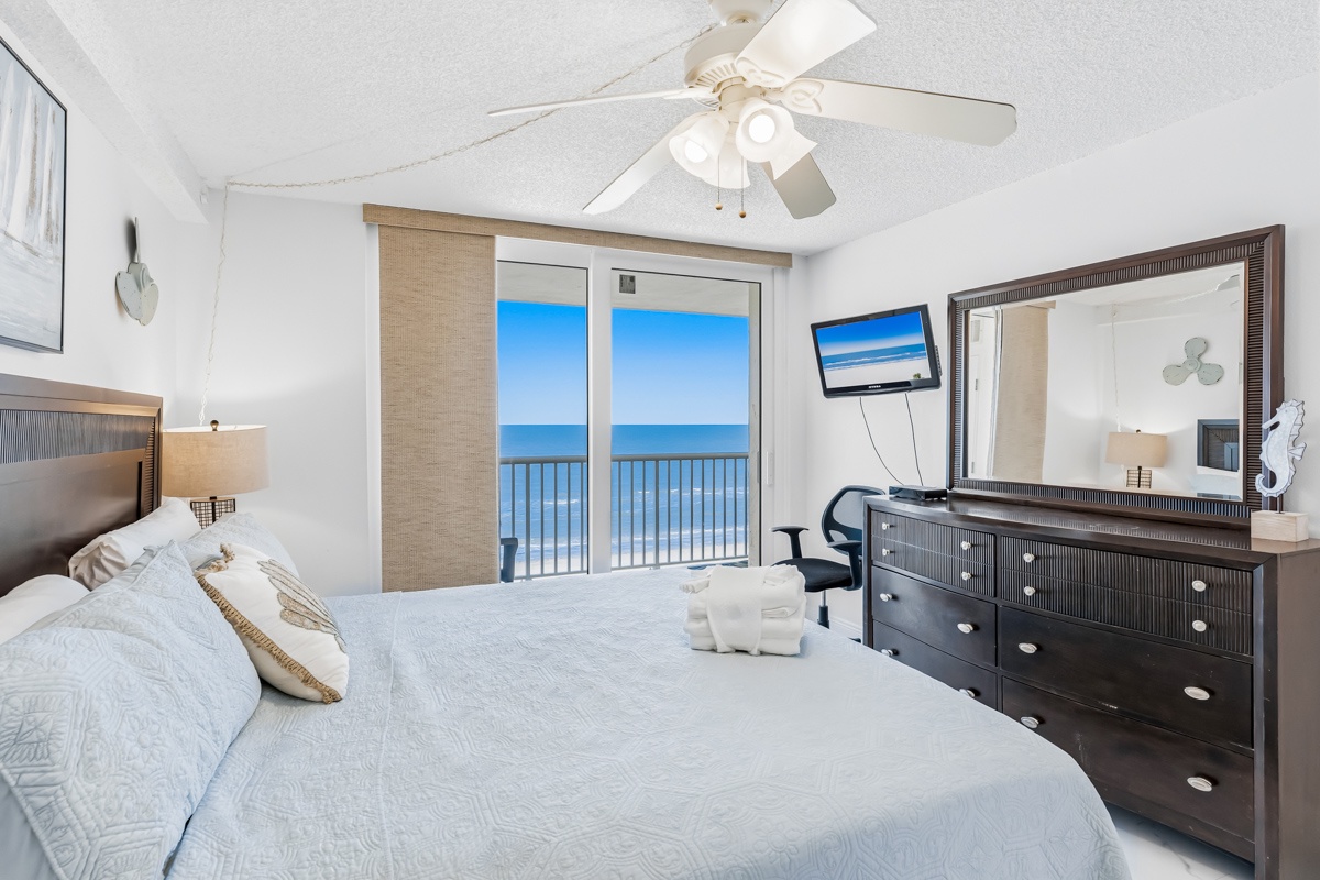 Your oceanfront bedroom offers stunning sea views through sliding doors, complete with ceiling fan and TV for ultimate comfort.