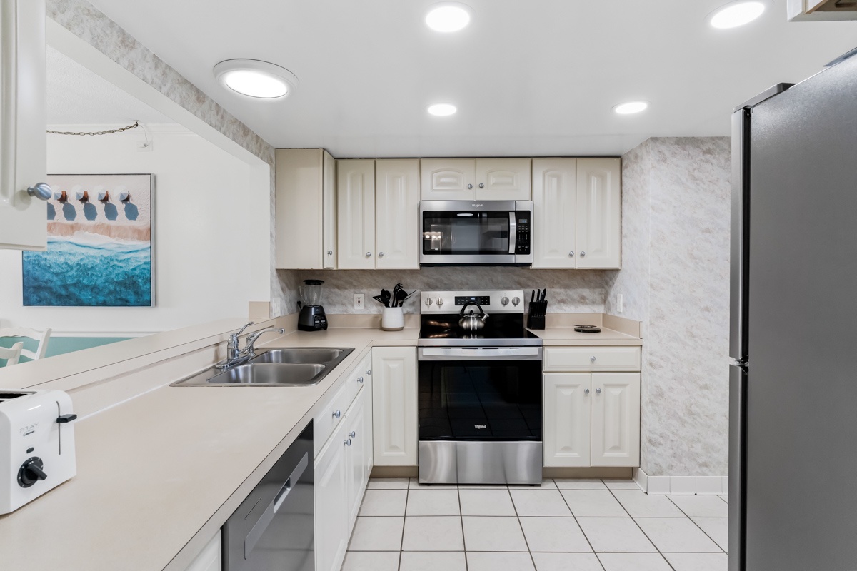Your fully equipped kitchen awaits with stainless steel appliances, coastal artwork, and everything you need to prepare meals during your beach getaway.