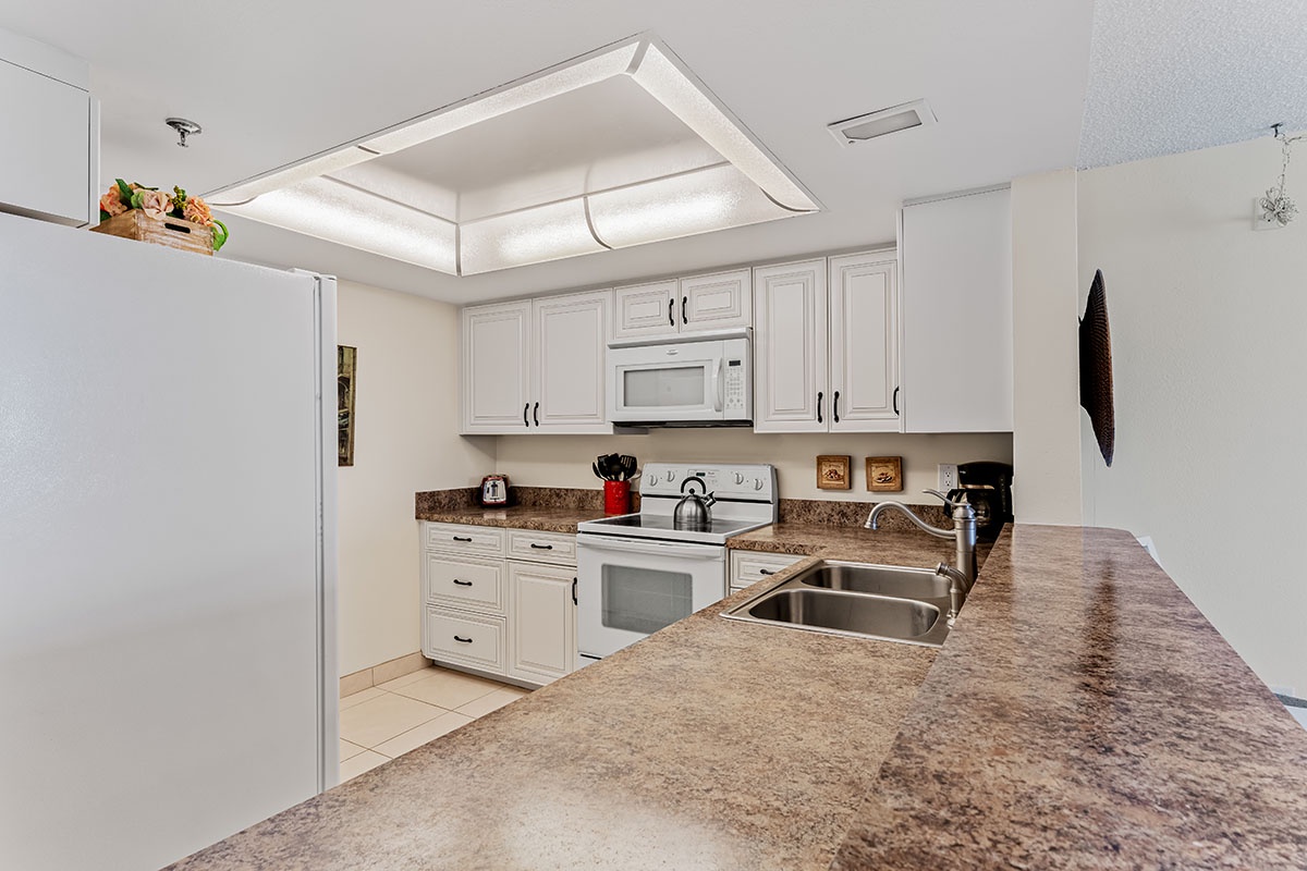Your fully equipped kitchen features granite countertops, white cabinetry, and modern appliances perfect for preparing meals during your stay.