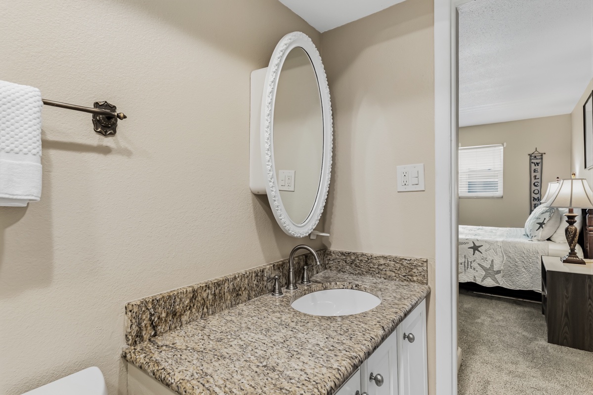 Your private en-suite features elegant granite counters and a charming oval mirror—a serene spot to start each morning before exploring the coast.