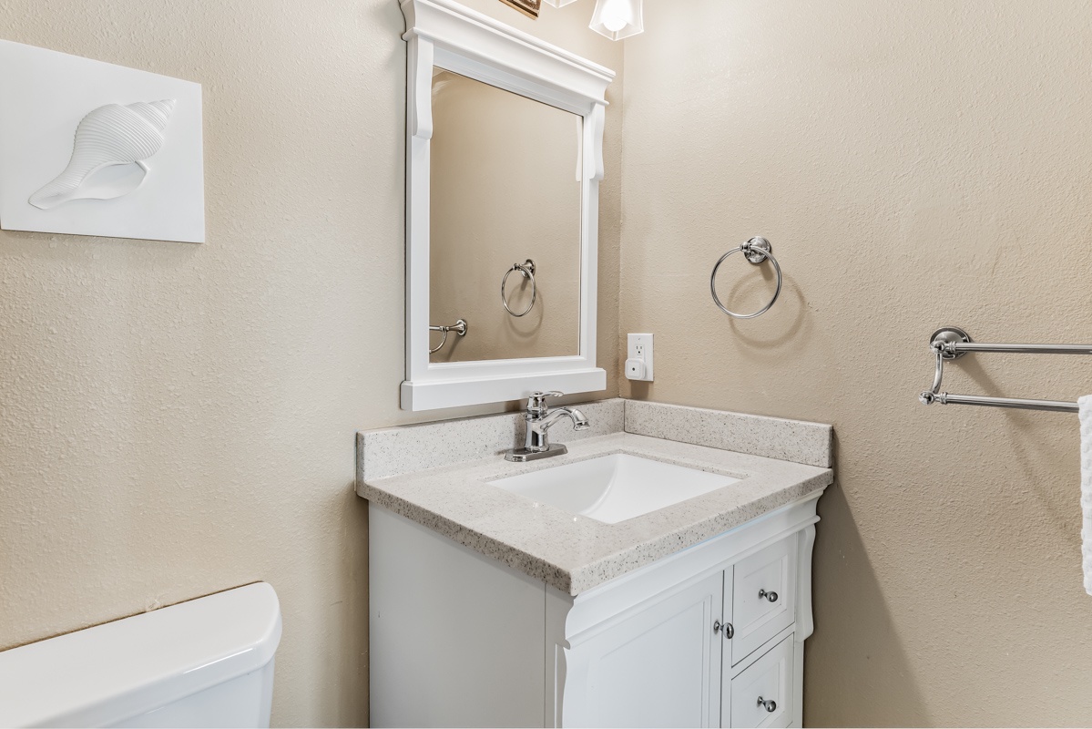Step into your private bathroom and freshen up at this bright vanity area with a clean sink and plenty of counter space. Enjoy modern fixtures and thoughtful coastal touches that keep everything you need close at hand.