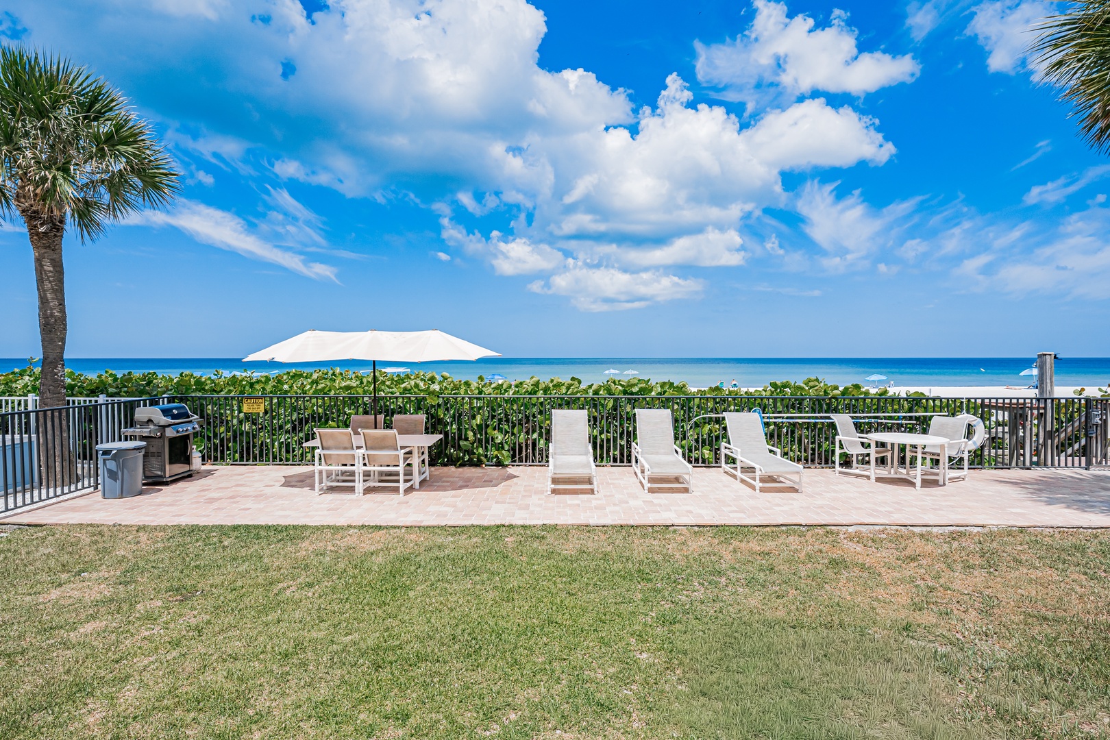 This oceanfront setting features a spacious lawn, lounge seating, dining furniture, and BBQ grill, all perfectly positioned to enjoy stunning turquoise water views and coastal breezes.