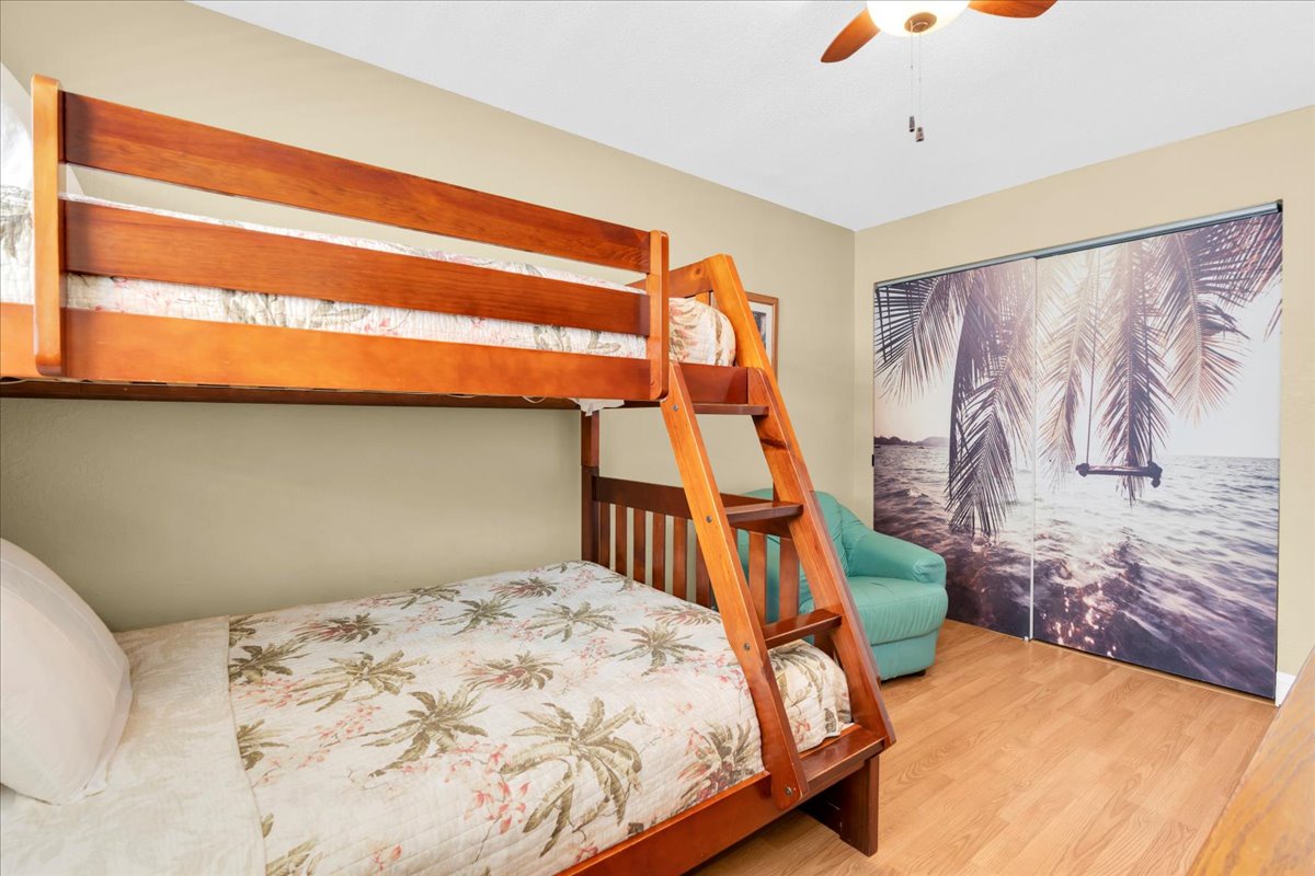 Your family will love this coastal-inspired bedroom with warm wood bunk beds, a cozy reading chair, and tropical touches that bring beach vibes indoors.