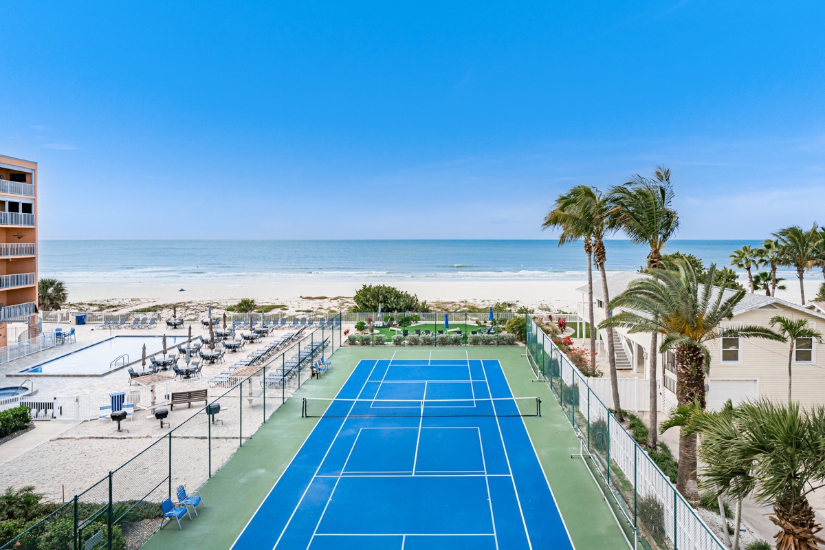 Beachfront resort featuring tennis courts, palm trees, and direct beach access with pristine white sand and turquoise waters.
