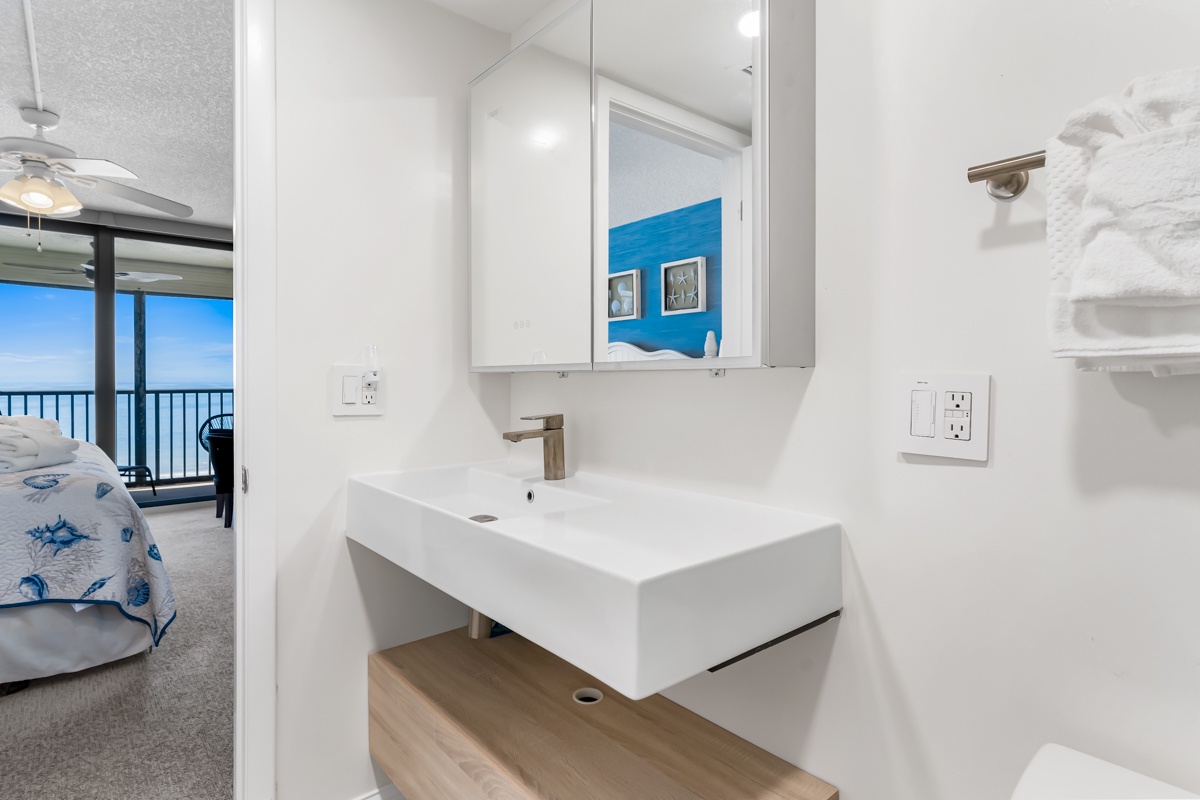 Your modern bathroom offers a sleek white vanity with brushed nickel fixtures, combining coastal style with contemporary convenience. Crisp white walls and smart storage make freshening up a pleasure.