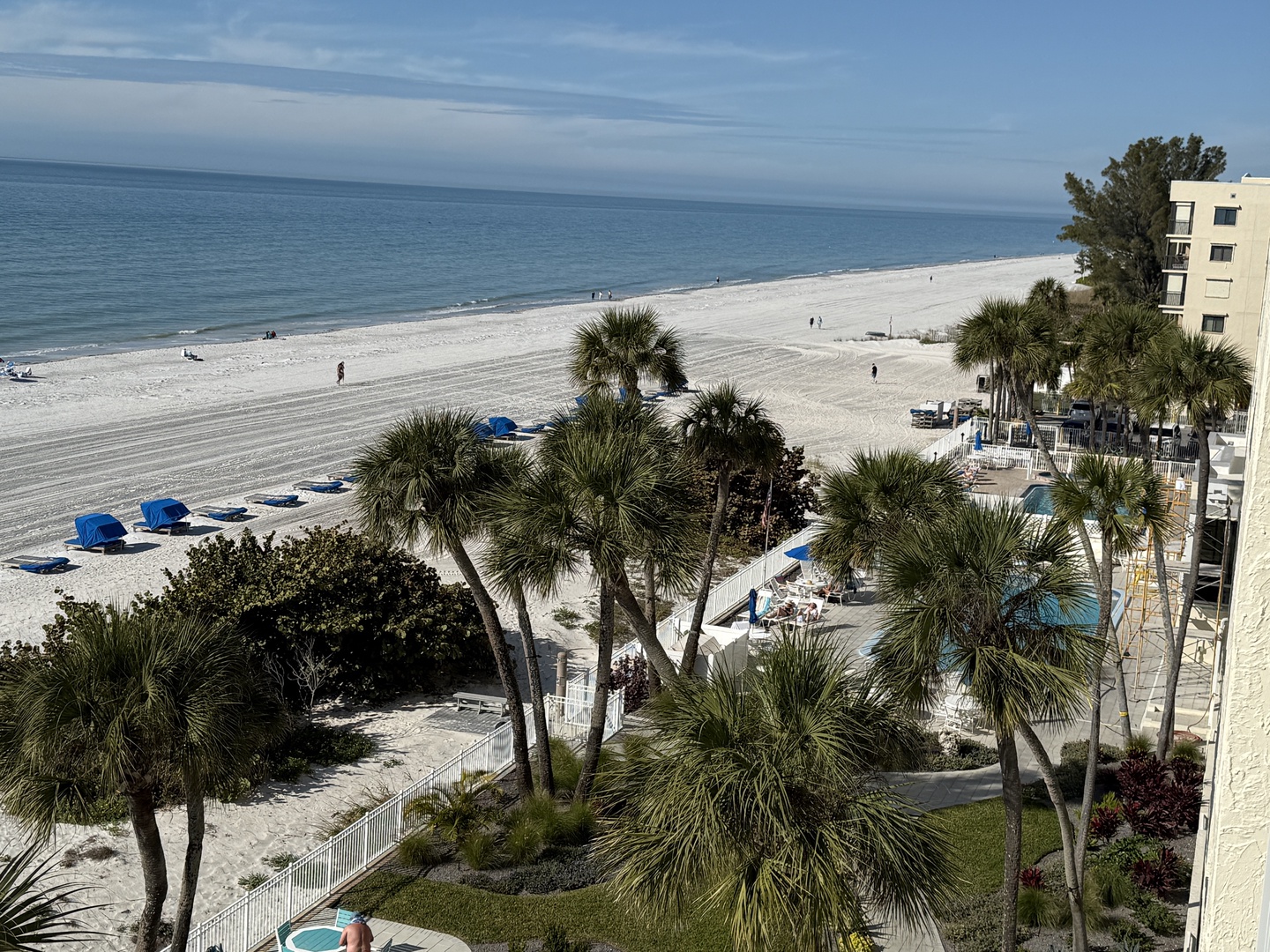 Beachfront property with white sand beach, palm trees, and crystal blue waters stretching to the horizon.
