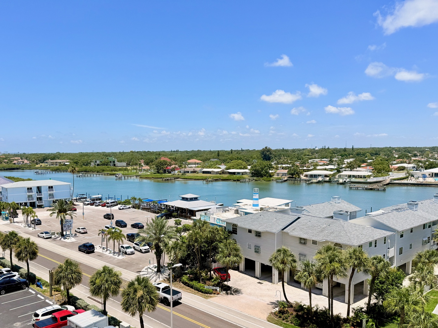 Aerial view of the waterfront property nestled along calm canal waters, surrounded by lush tropical palms and coastal homes.