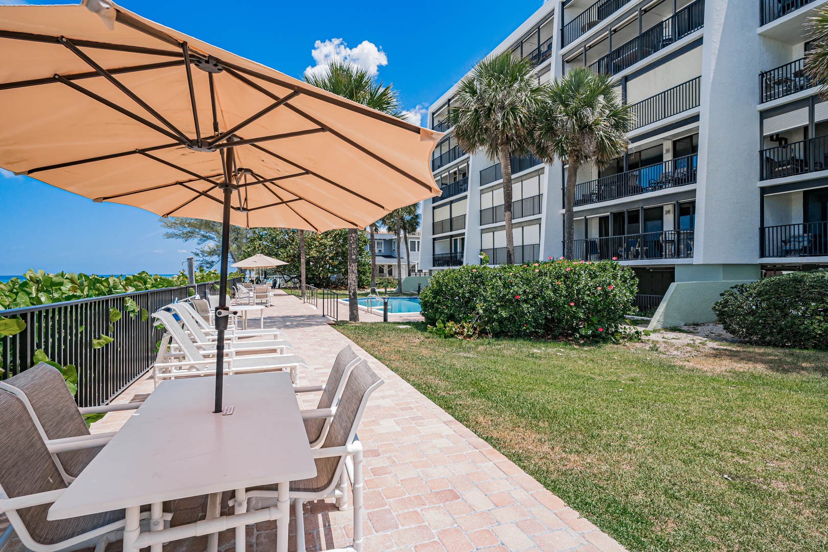 A mid-rise beachfront property with lush palm trees, manicured lawns, and pool access, offering convenient access to coastal relaxation.