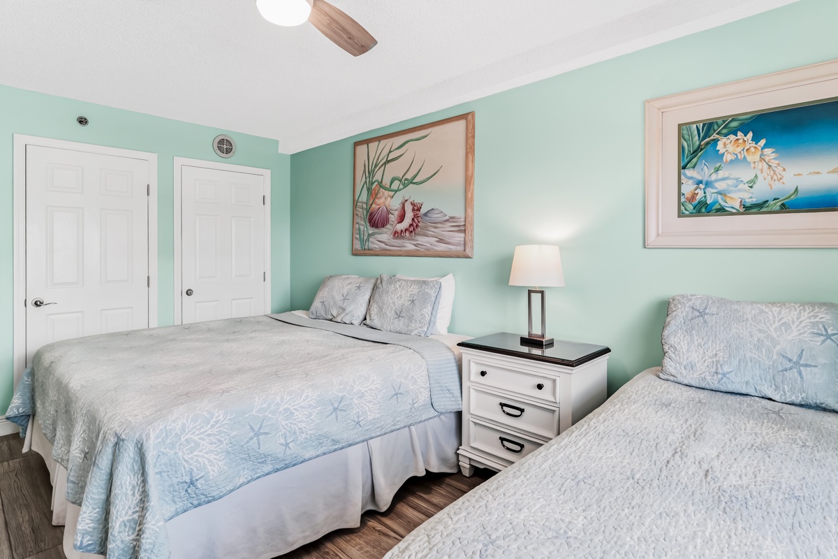 Drift off in your King/Twin coastal-inspired bedroom with two plush beds, soft ocean hues, and charming seaside artwork that sets a serene, beach-house mood.