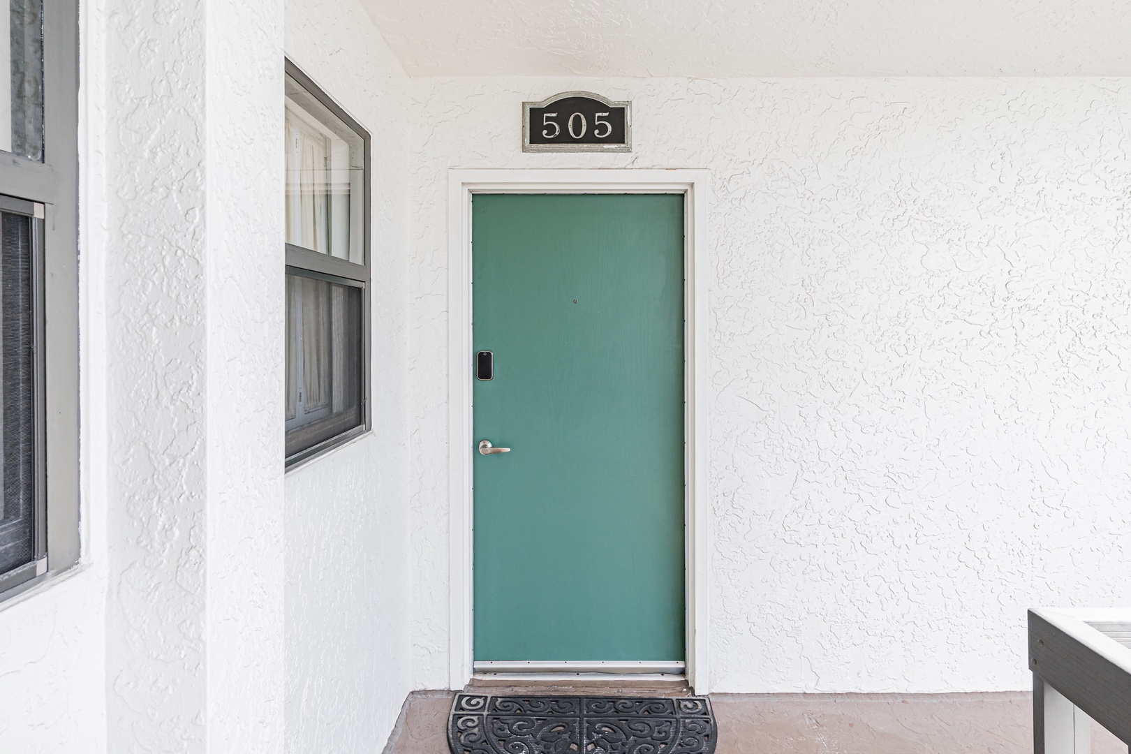 Unit 505 welcomes you with a cheerful turquoise door and clean white exterior, marking the start of your vacation stay.