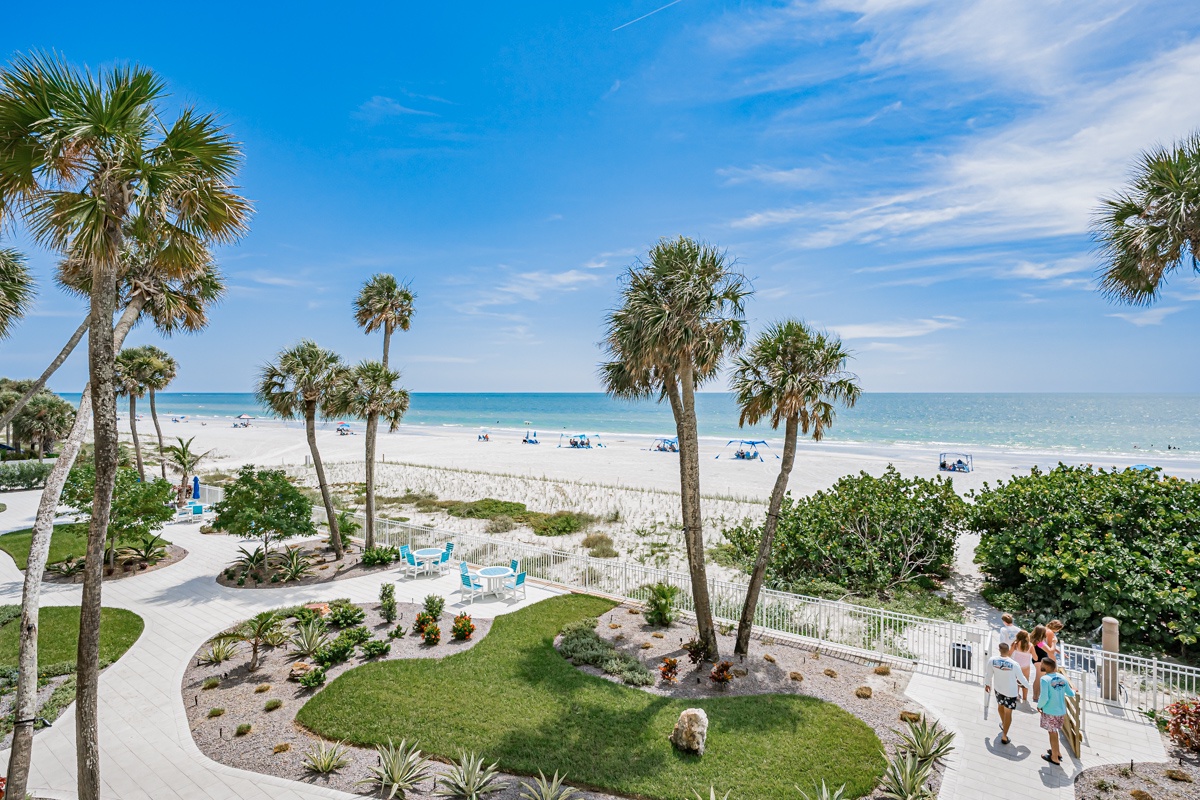Pristine beachfront with swaying palms, powdery white sand, and turquoise waters, framed by lush tropical landscaping and inviting walkways leading to the shore.
