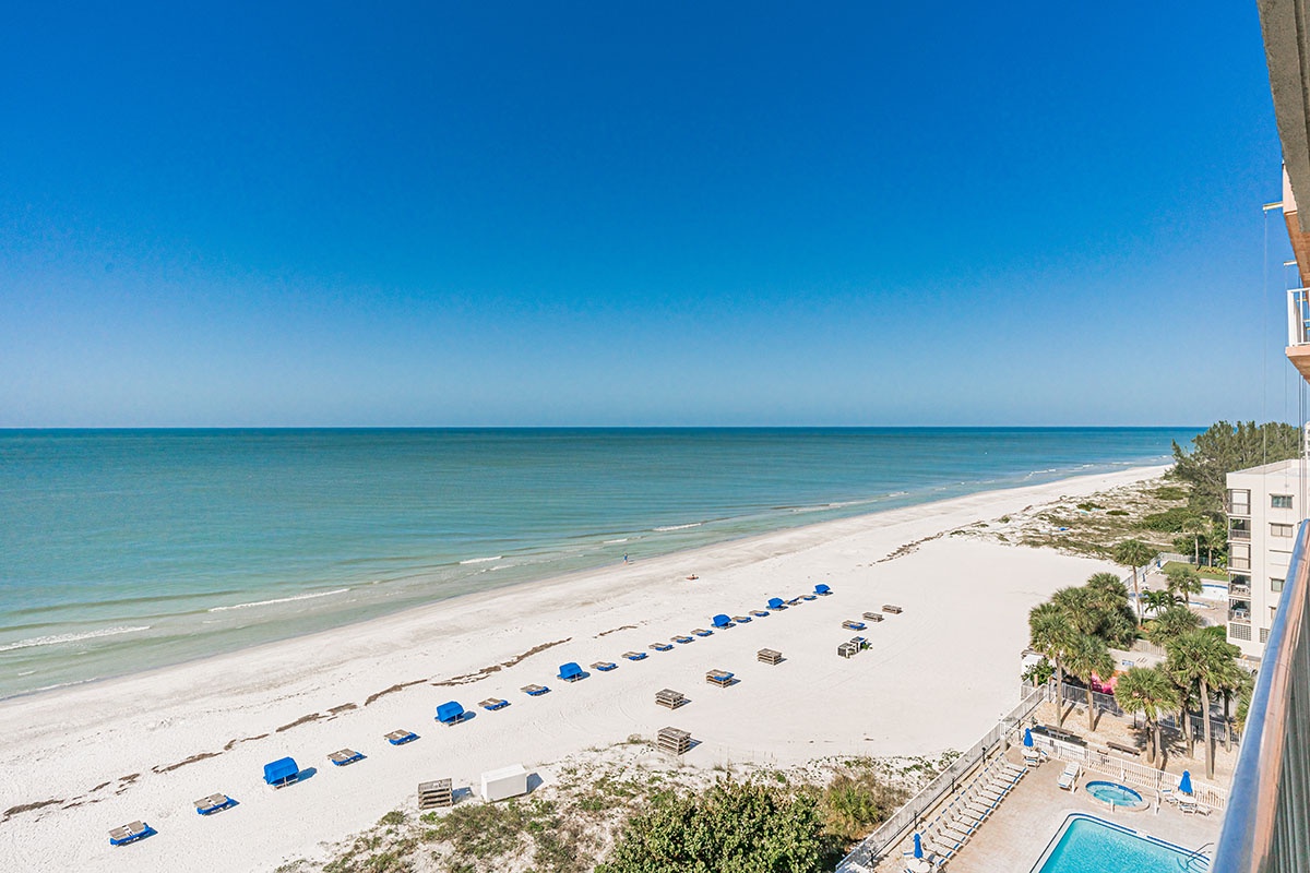 Stunning beachfront views showcase pristine white sand, turquoise waters, and beach chairs awaiting your arrival along this beautiful coastline.