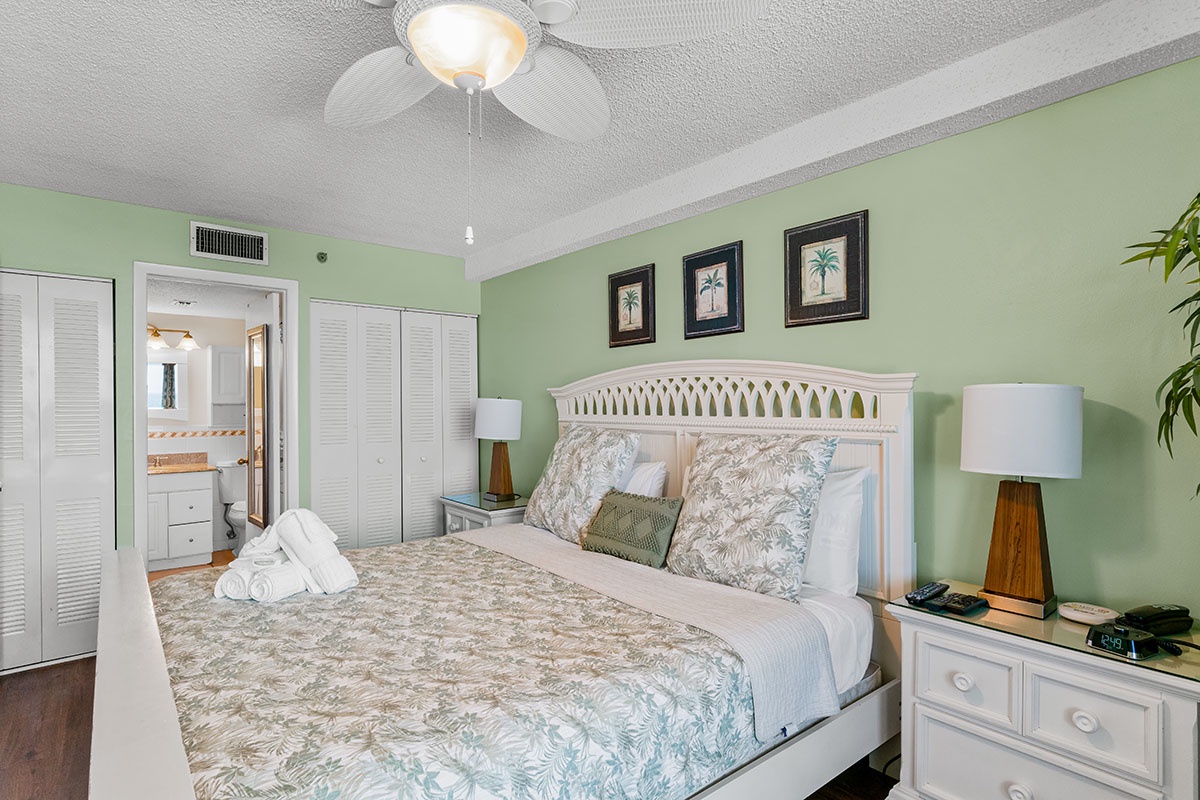 Your tropical bedroom oasis awaits with soothing mint walls, crisp white furnishings, and tropical art creating a peaceful coastal retreat.