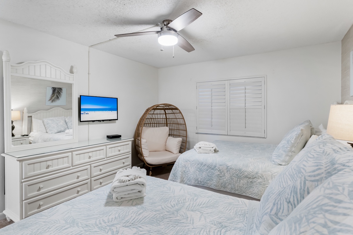 Unwind in your bright, coastal-inspired bedroom, where soft linens and a cozy hanging chair invite you to relax after a day of adventure.