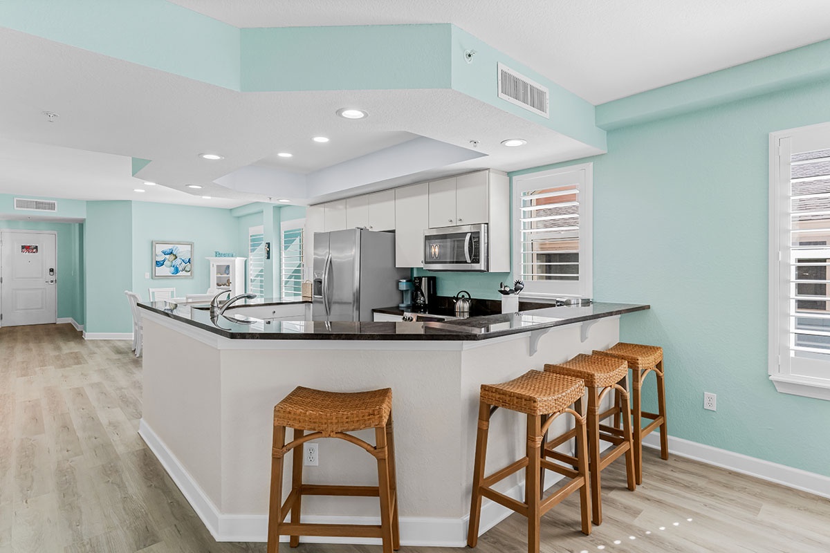 Your spacious kitchen features granite countertops, stainless steel appliances, and coastal-style seating perfect for morning coffee or evening cocktails.