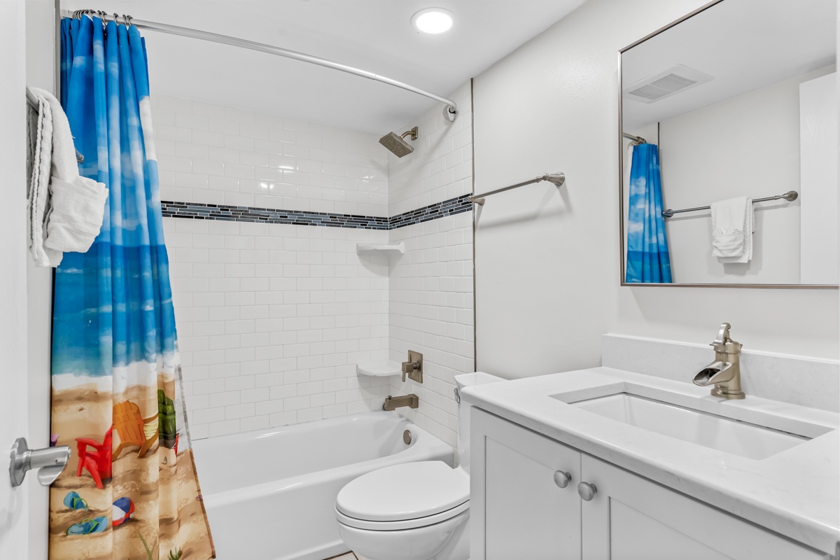 Refresh in your modern bathroom with a deep soaking tub, subway tile, and cheerful beach-themed touches that make every morning feel like vacation.