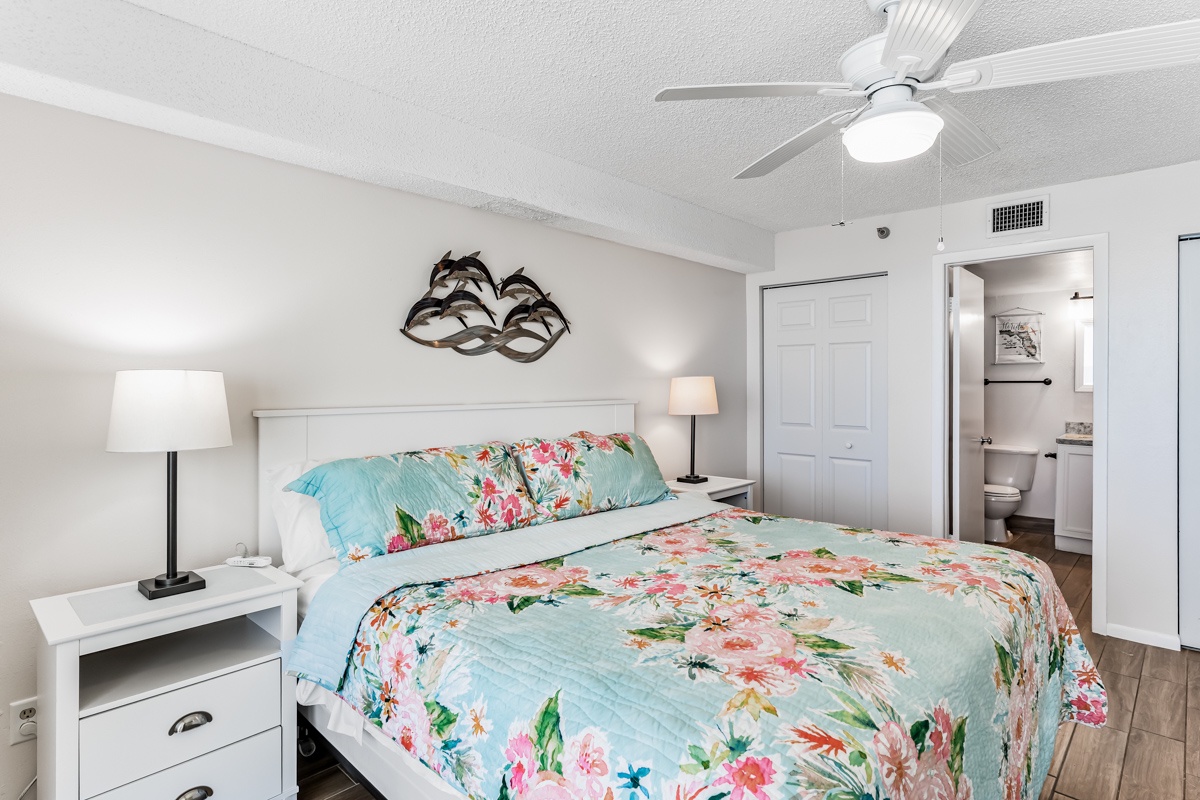 Picture yourself settling into this serene bedroom, where the ceiling fan hums softly and the colorful floral bedding invites restful sleep. Your peaceful retreat awaits.