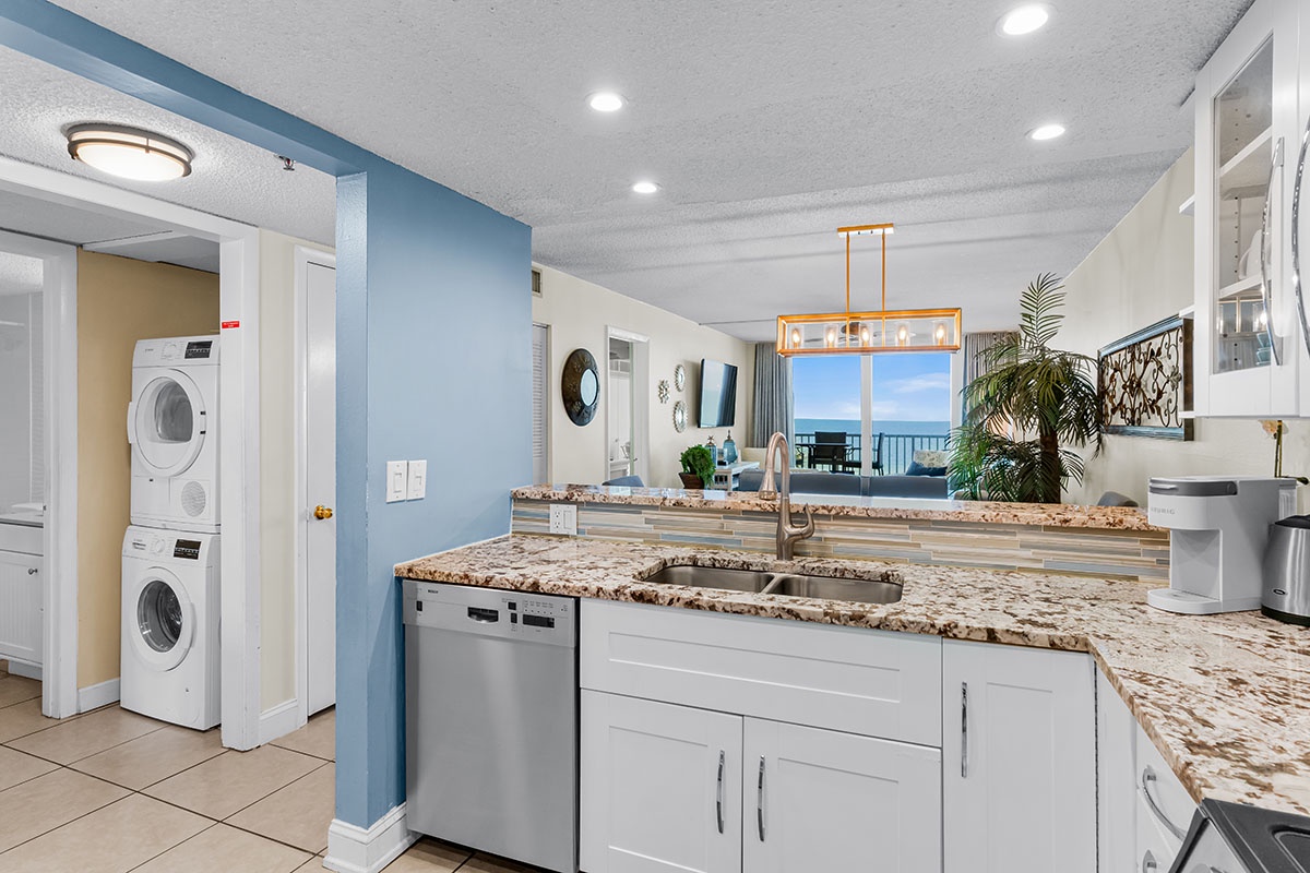 Your spacious kitchen features granite countertops and modern appliances, with convenient laundry access and stunning ocean views through the window.