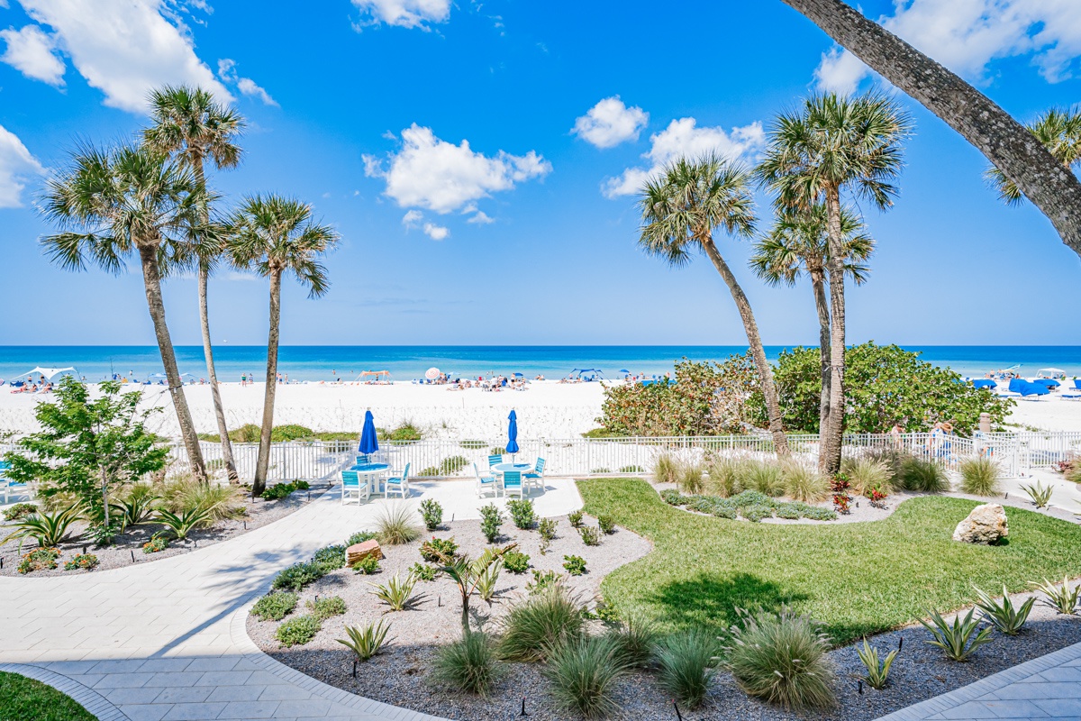 Beachfront property with direct access to pristine white sand and turquoise waters through tropical palm-lined grounds.