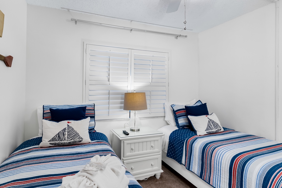 Your bright and breezy guest bedroom features twin beds with crisp nautical linens, perfect for family or friends. Shuttered windows and soft lighting create a restful haven after sunny beach days.