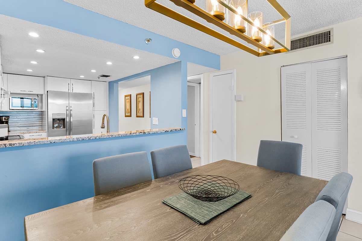 Gather around your elegant dining table where coastal blue accents and modern lighting create the perfect atmosphere for memorable meals together.