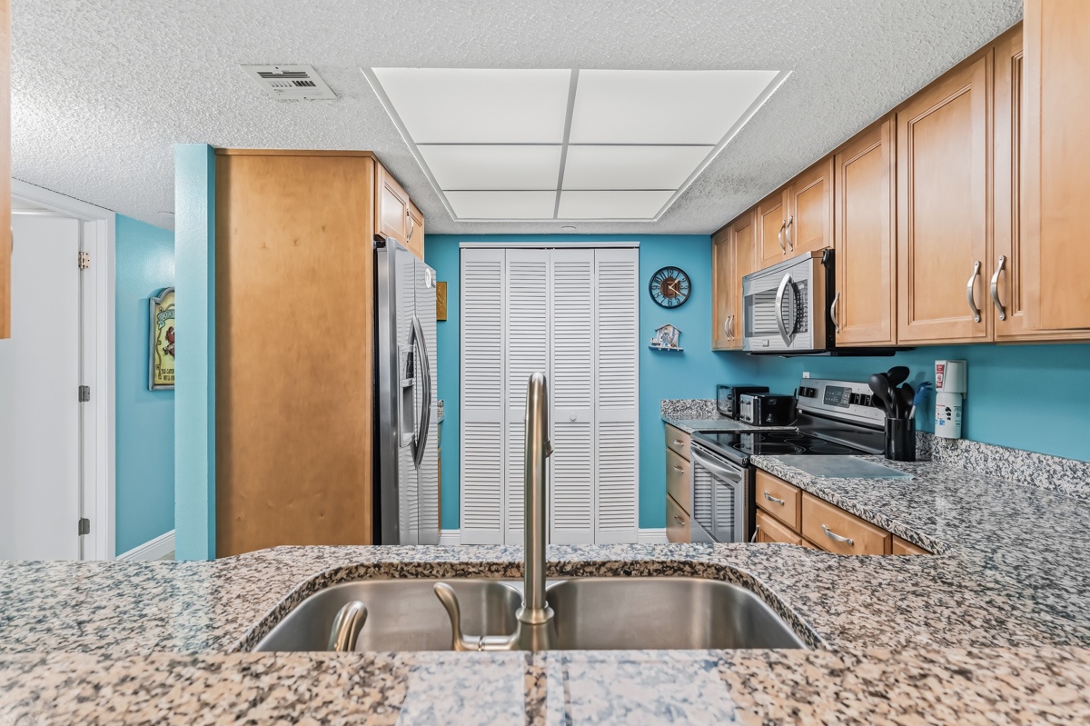 Your fully equipped kitchen features speckled granite countertops, warm wood cabinetry, and cheerful turquoise walls that make meal prep feel like a breeze in paradise.