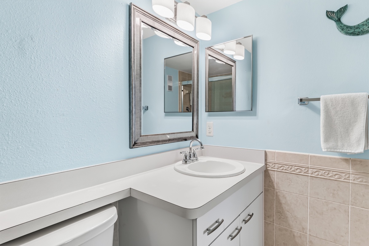 Refresh in your bright coastal-inspired bathroom, featuring calming blue walls, crisp white accents, and a whimsical mermaid tail décor that captures the beachy vibe.