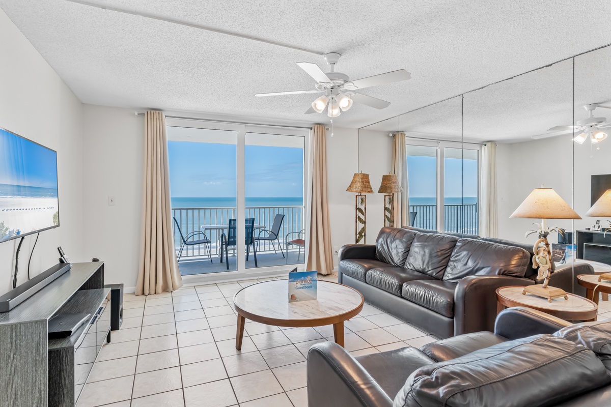 Your spacious living room opens to stunning ocean views through floor-to-ceiling windows, with comfortable leather seating and private balcony access.