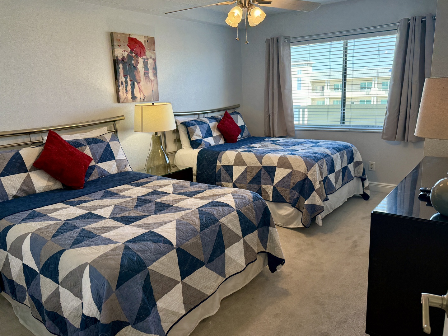 Rest peacefully in your 2 double-bed room featuring geometric quilts, warm lighting, and modern amenities for a comfortable stay.
