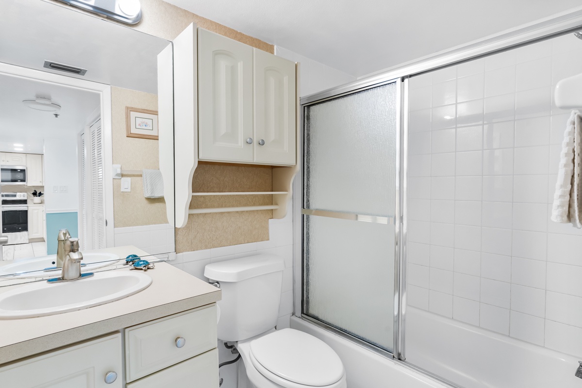 Your clean bathroom features everything you need with a spacious shower, convenient vanity storage, and fresh white tiles.