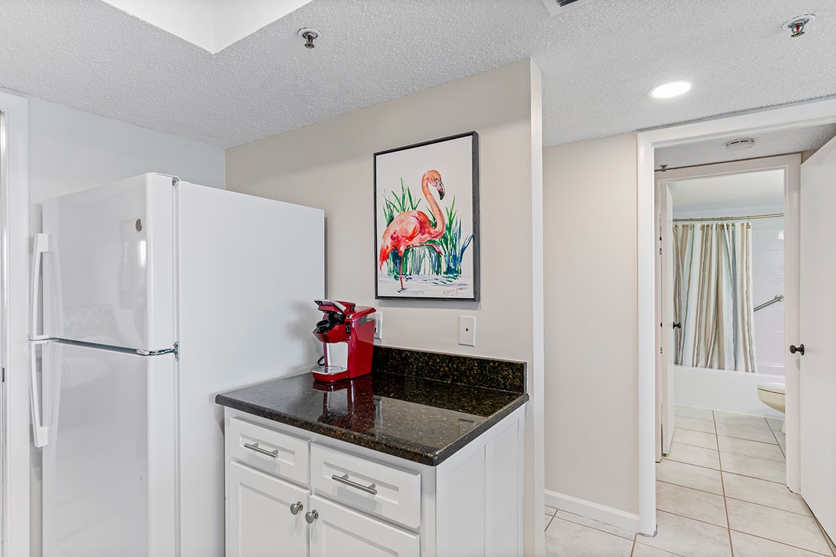Your compact kitchenette offers everything you need with granite counters and modern appliances, perfectly complemented by cheerful flamingo art.