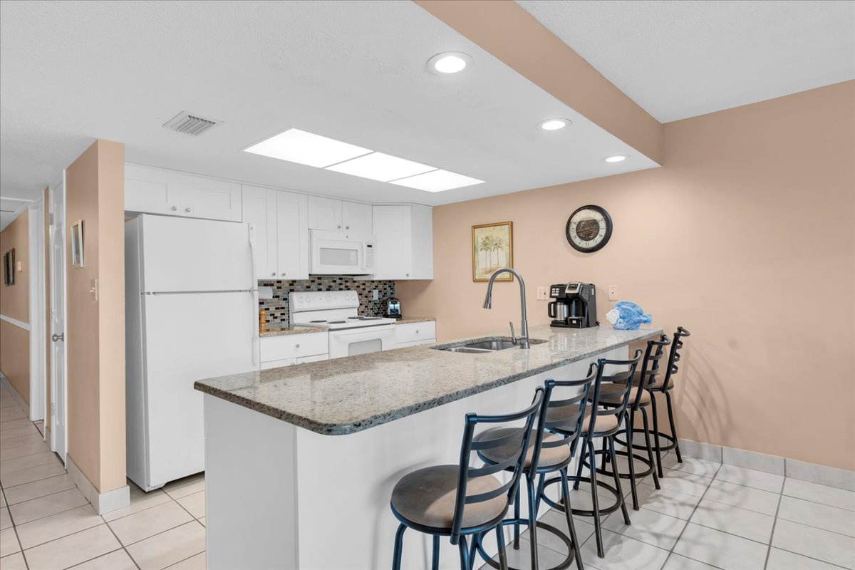 Your fully equipped kitchen features granite countertops, modern appliances, and a spacious breakfast bar with seating for four—perfect for morning coffee or casual dining together.
