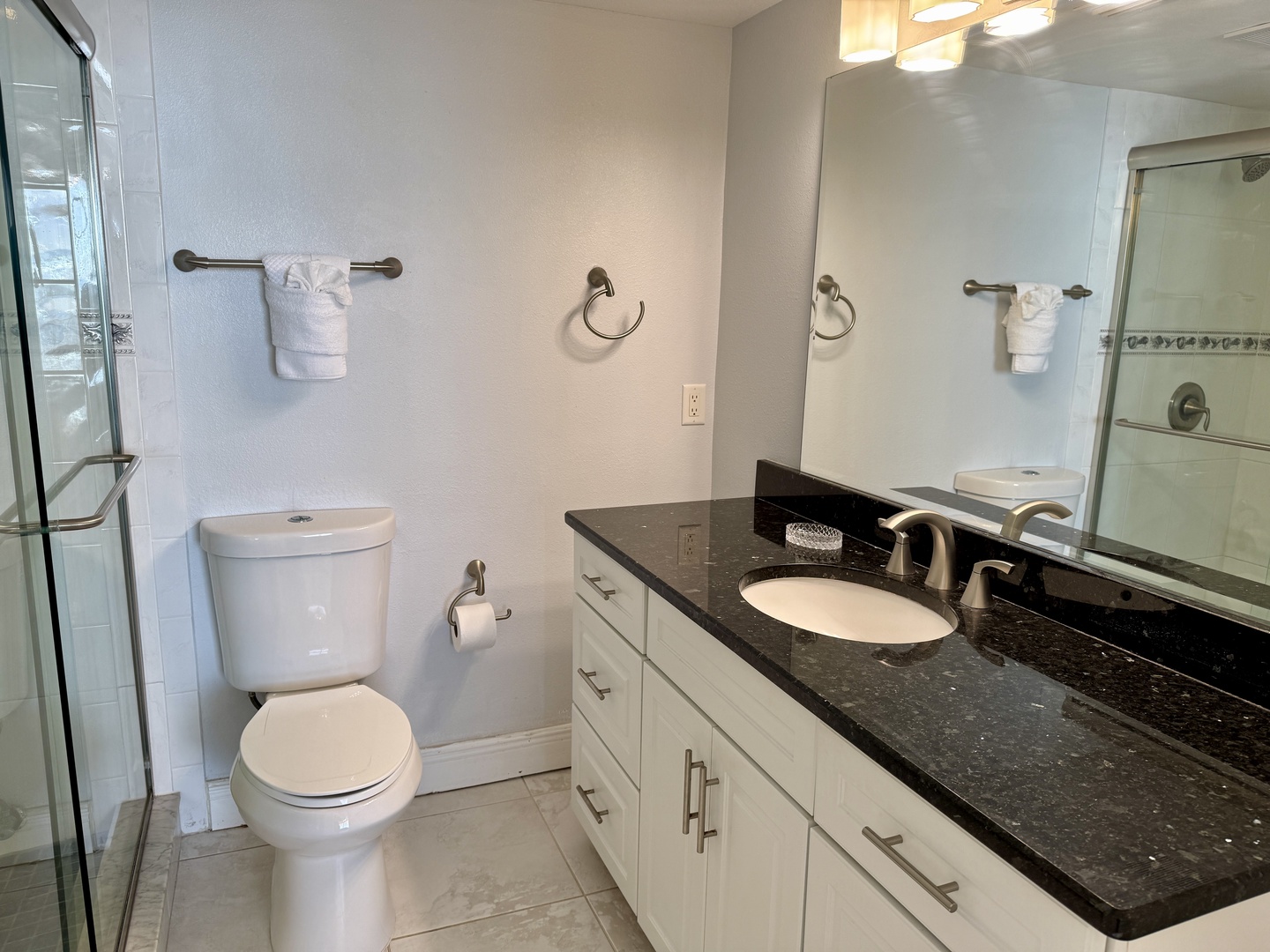 Refresh in your beautifully appointed bathroom featuring elegant granite countertops, crisp white cabinetry, and a spacious glass shower—your perfect sanctuary.