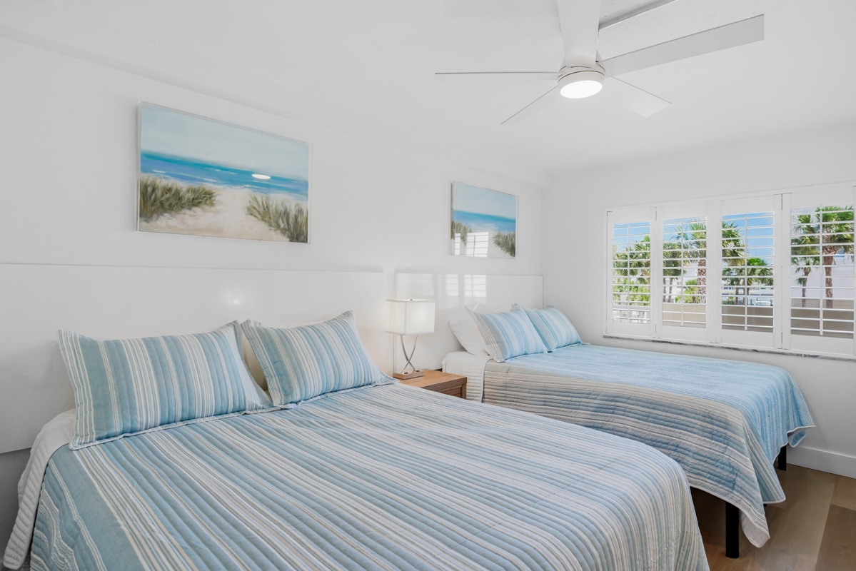 Drift off to sleep in your serene coastal bedroom with 2 Queen beds dressed in soft blue linens and ocean artwork.