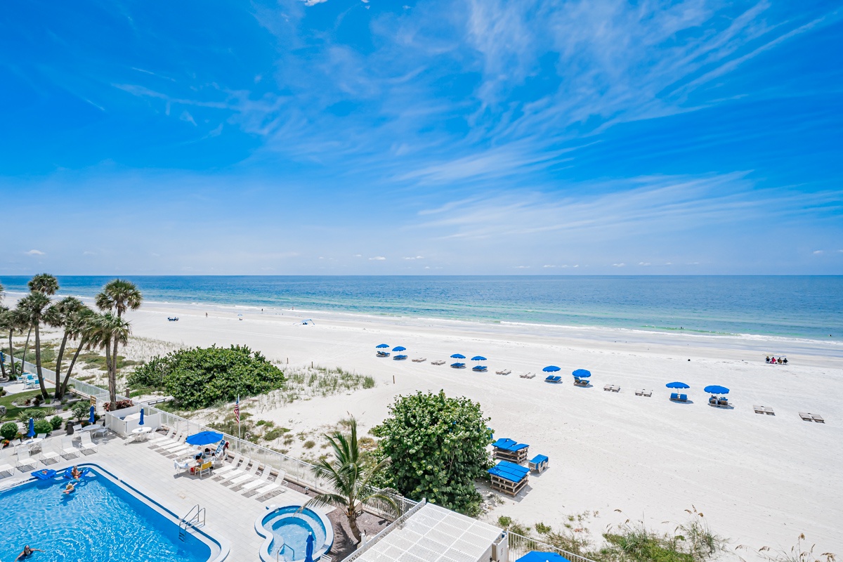 Stunning beachfront location featuring white sand beach, coastal palms, and sparkling blue waters. The pool and beachside seating create your perfect Gulf Coast escape.