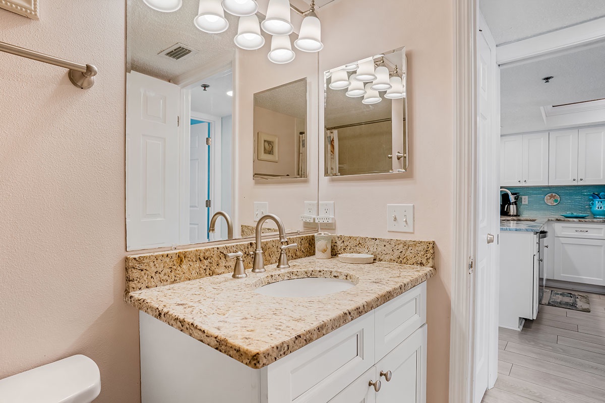 Dual vanities with granite counters and stylish lighting create your perfect morning routine in this elegant bathroom space.