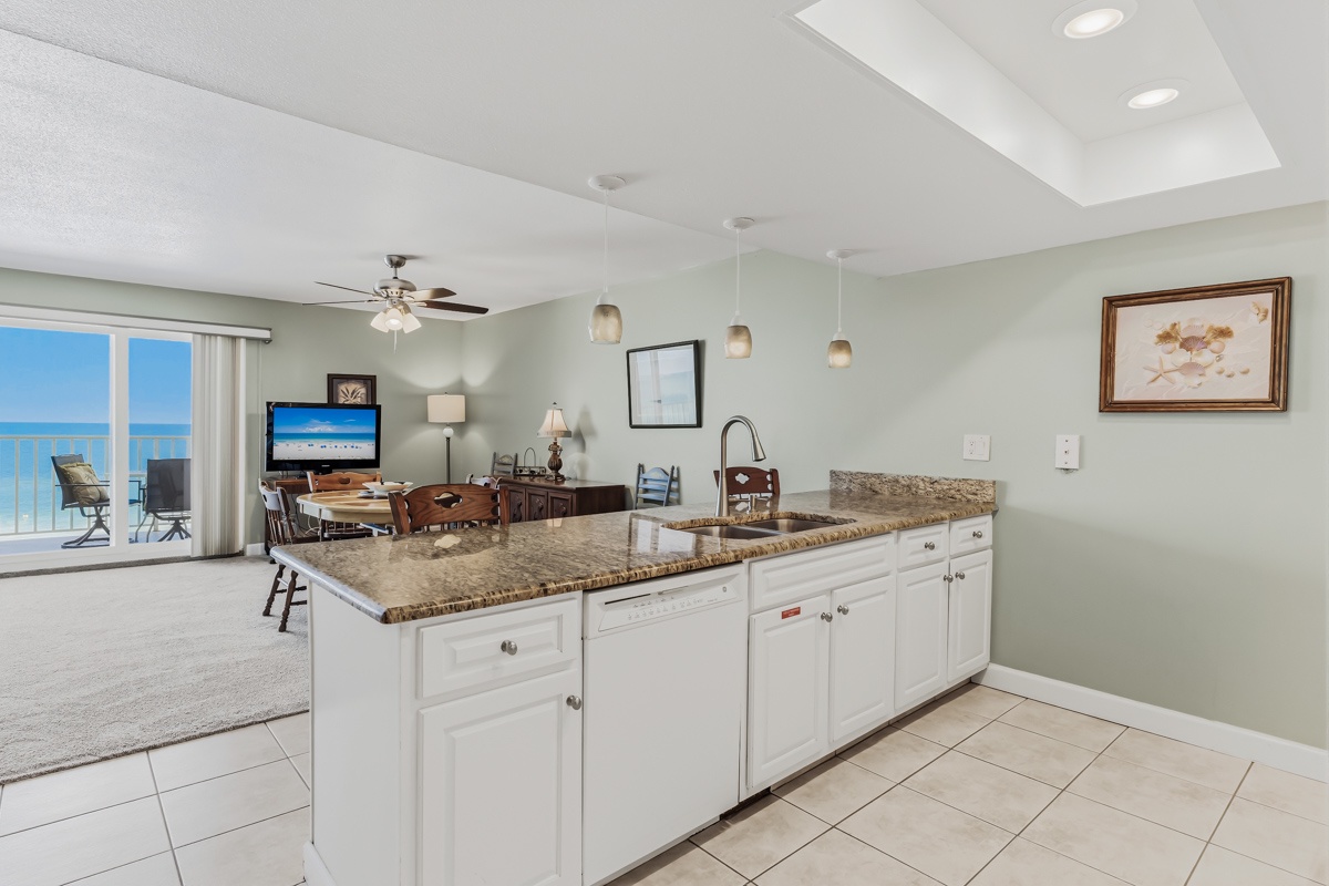 Your kitchen opens to an inviting space where natural light pours in, highlighting granite counters and modern fixtures. Beyond the living area, a private balcony frames stunning ocean views—perfect for your morning coffee or evening sunset.