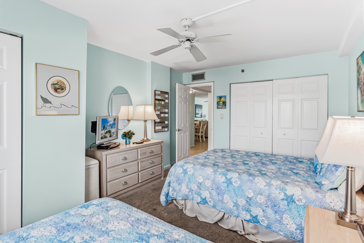 Drift off in this serene coastal bedroom, where soft sea-blue tones and gentle breezes from the ceiling fan help you unwind. Twin beds and ample storage make your stay effortlessly comfortable.